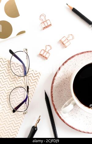 White desk with mug of coffee, paper clips, glasses, notepads, calligraphic pen and pencils on white desk Stock Photo