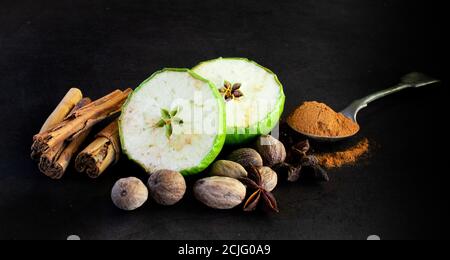 Fresh and dried green applies and whole spices on dark background Stock Photo