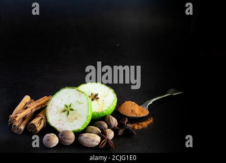 Fresh and dried green applies and whole spices on dark background Stock Photo