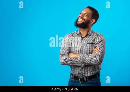 Smiling black man with folded arms posing on blue background Stock Photo