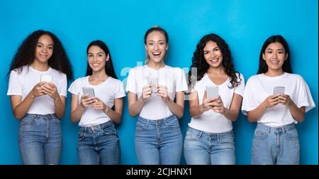 Five Multiracial Women Using Smartphones Over Blue Studio Background, Panorama Stock Photo