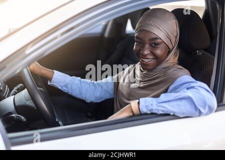 Portrait of happy young black confident muslim woman posing in her car Stock Photo