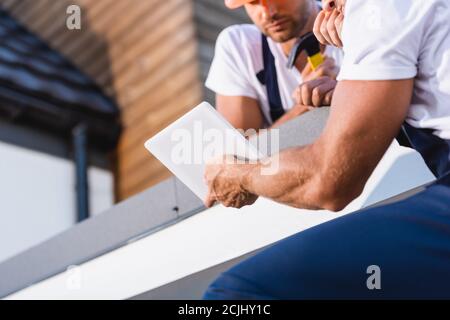 Cropped view of builders using digital tablet on roof of house Stock Photo