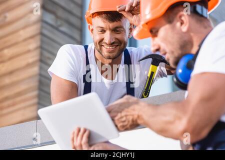 Selective focus of handymen using digital tablet on roof of building Stock Photo