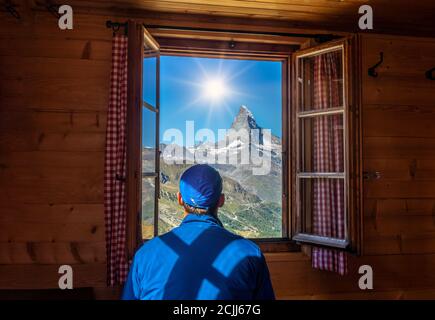 Guy looking at the mountains Matterhorn or Cervino in a luxury room in a hostel at Stelliesee in Switzerland Stock Photo