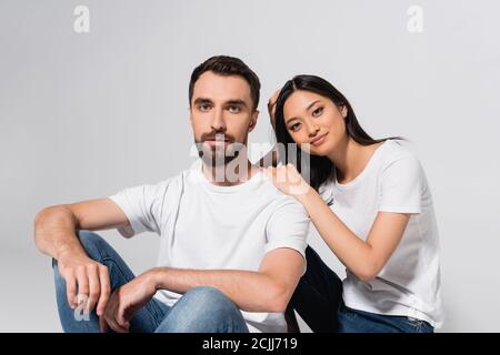 young asian woman looking at camera while sitting near boyfriend isolated on white Stock Photo