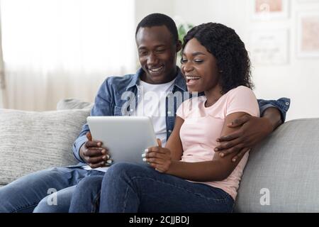 Smiling african man and woman websurfing together at home Stock Photo