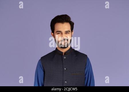 Handsome Indian guy expressing suspicion over violet background Stock Photo