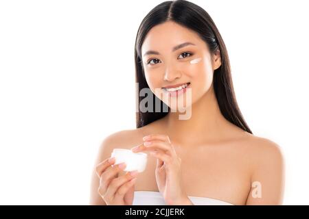 brunette asian woman touching cosmetic cream while looking at camera isolated on white Stock Photo