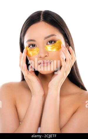 brunette asian woman looking at camera while touching golden eye patches isolated on white Stock Photo