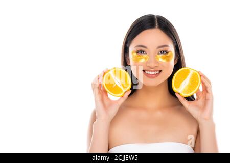 young asian woman with golden eye patches on face holding halves of fresh orange isolated on white Stock Photo