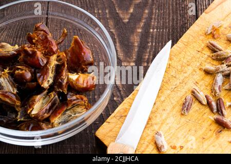 Hushaf - date milk, traditional Ramadan dish, cooking, ingredients, pitted dates in a plate, knife and seeds on a cutting board on the wooden table Stock Photo