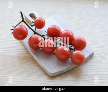 Cherry tomatoes on a wooden cutting board. Closeup image Stock Photo