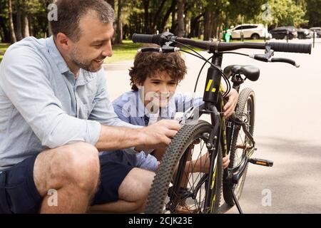 Closeup portrait of cheerful dad and son fixing bike Stock Photo