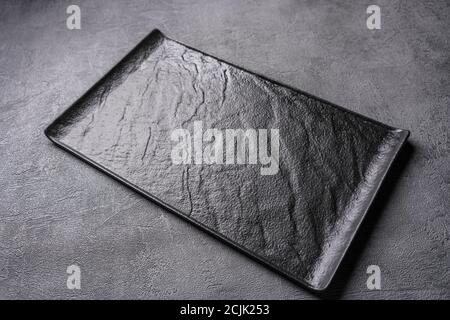Empty black cutting board of stone on a gray concrete grunge textured background. Copy space Stock Photo