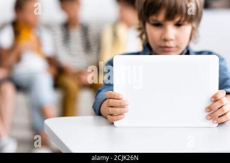 Selective focus of schoolboy using digital tablet at desk in classroom Stock Photo