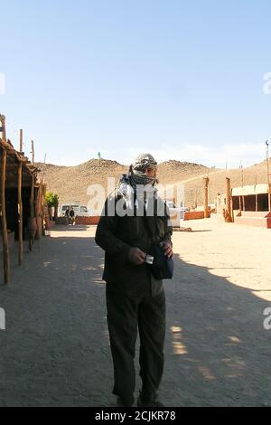 masked senior taking a coffee ion Bedouins village, Sahara desert, Egypt Stock Photo