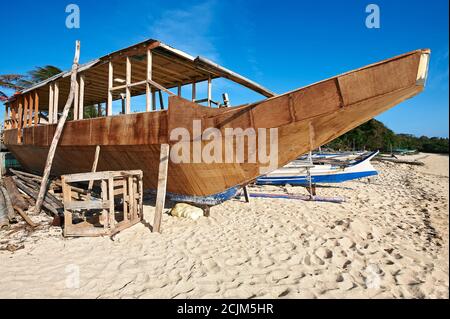 A wooden filipino banca style outrigger boat is being build along a sandy beach on Boracay Island, Philippines, Asia Stock Photo