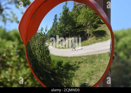 Curved Mirror, Distorting Mirror, Round Road Security or Road Safety Mirror Reflecting Deformed Reflection or Mirror Image of Country Road & Landscape Stock Photo