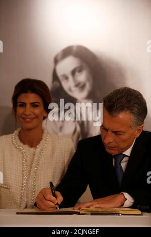 Argentina's President Mauricio Macri and his wife Juliana Awada sign the guest book as they sit in front of an image of Anne Frank during a visit to the Anne Frank House in Amsterdam, Netherlands, March 27, 2017. REUTERS/Cris Toala Olivares