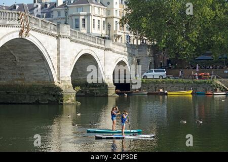 two female paddle boarders on the river thames close to richmond bridge, southwest london, england Stock Photo