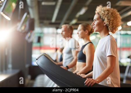 Group of healthy people exercising on treadmills during sports training in health club Stock Photo