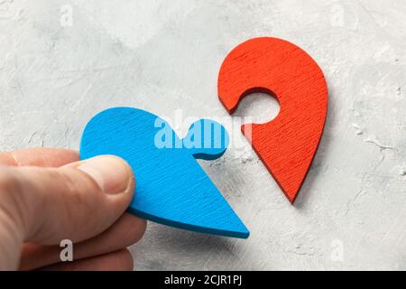 Heart puzzle The two halves of the heart of a man and a woman joined together. Two parts of love. Couple of lovers. Male hand holding puzzle piece. Stock Photo