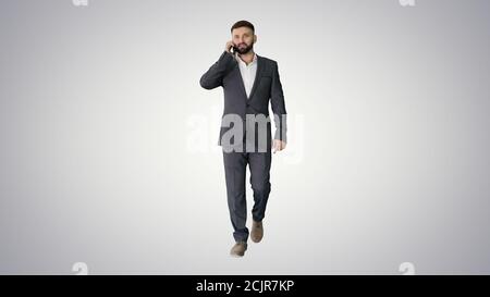Businessman walking and making a call on gradient background. Stock Photo