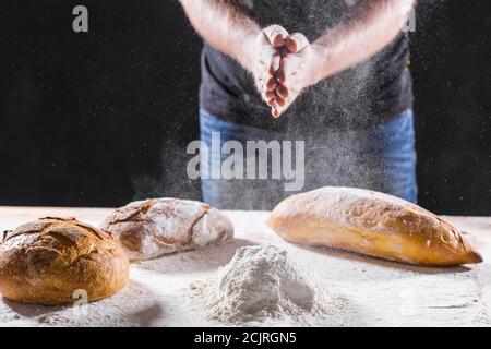 Baker cooking bread. Man slaps flour. Food concept. Stock Photo
