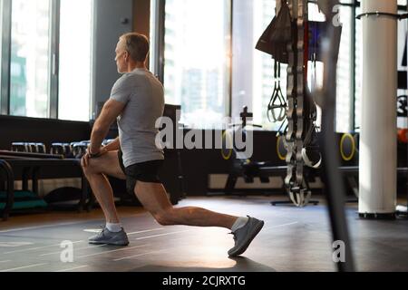Rear view of mature man doing stretching exercises before sports training in gym Stock Photo