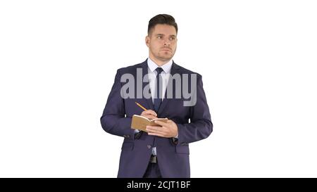 Handsome experienced manager writing in notebook his ideas while walking on white background. Stock Photo