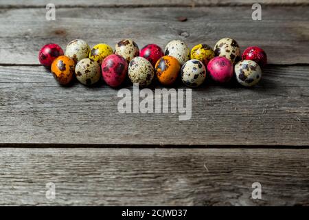 Multi-color dyed easter eggs arranged in a row on wooden background. Stock Photo