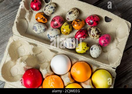 Dyed easter eggs in cardboard box on wooden background. Stock Photo