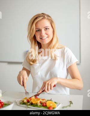 close up portrait of gorgeous fair-haired woman having supper and looking at the camera. beauty and health. girl runs culinary show Stock Photo