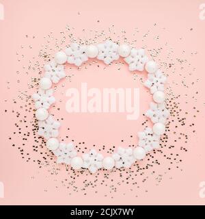 Holiday round frame made of christmas white snowflakes on pink background. Christmas composition, wallpaper. Flat lay, top view Stock Photo