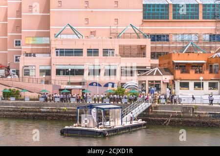 yokosuka, japan - july 19 2020: People waiting in row at the pontoon of the cruise of Yokosuka Naval Port in front of the Coaska Bayside Stores in the Stock Photo