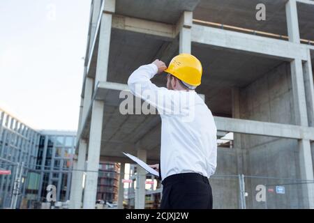 Man Controlling Building. Builder making marks in Clipboard. House Building Stock Photo