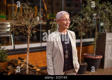 a nice businesswoman is waiting for colleague in front of the restaaurant. side view shot Stock Photo