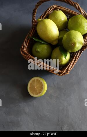 Fresh lemons on wicker basket isolated on grey background. Top view. Selective focus. Copy space. Stock Photo