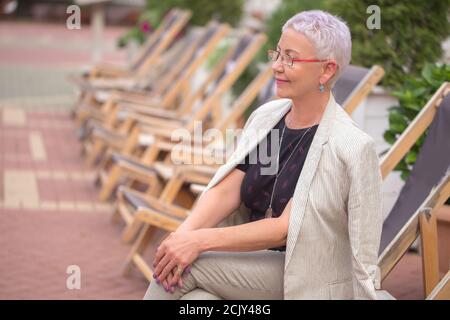 a pleasant mature woman in stylish clothes is waiting the concert ouside. side view photo Stock Photo