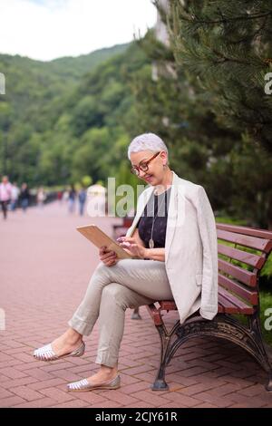 a cheerful woman typing her project on the tablet. job and internet concept. side view full length photo Stock Photo