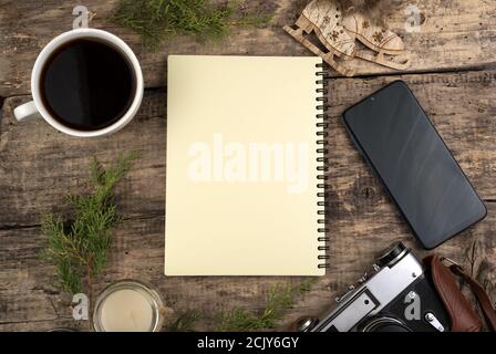 Cozy Christmas composition on a wooden background. Notepad, phone, coffee candle on a natural Board. Stock Photo