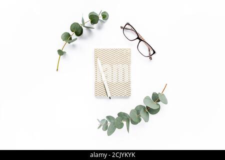 diary, pen, green leaves eucalyptus and glasses on white background. flat lay, top view Stock Photo
