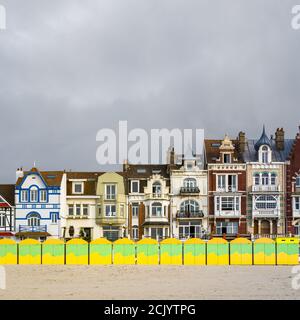 Colorful beach huts in front of historic seaside buildings Stock Photo