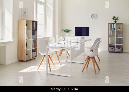 Interior of a modern white business office. Empty light spacious conference room in office with desk, chairs and computer for meetings or online calls Stock Photo
