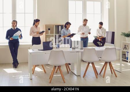 Serious busy employees reading financial reports while waiting for company manager Stock Photo