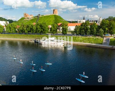 Stand up paddle boarders passing by Gediminas Tower, the remaining part of the Upper Castle in Vilnius. SUP getting popular in Vilnius, Lithuania. Spo Stock Photo