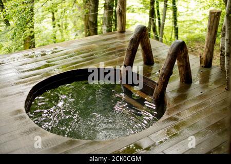 Wooden hot tub outdoors.close up photo.wooden bath in the forest. water treatment on landscape. water, health, wellness, relaxation concept Stock Photo