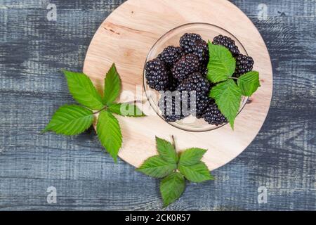 ripe blackberry with leaves on on dark blue wooden background Stock Photo