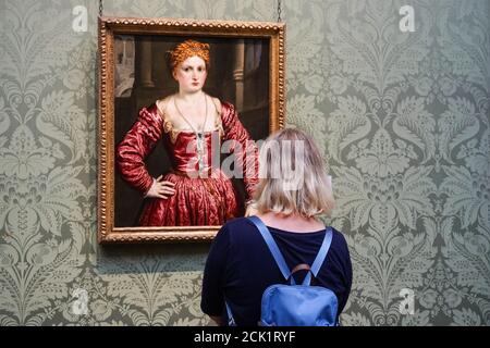Young woman looking at painting, Portrait of a Young Woman by Paris Bordone, at the National Gallery in London, England United Kingdom UK